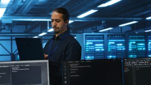 Manager,Overseeing,Server,Room,,Running,Code,On,Laptop,,Troubleshooting,And